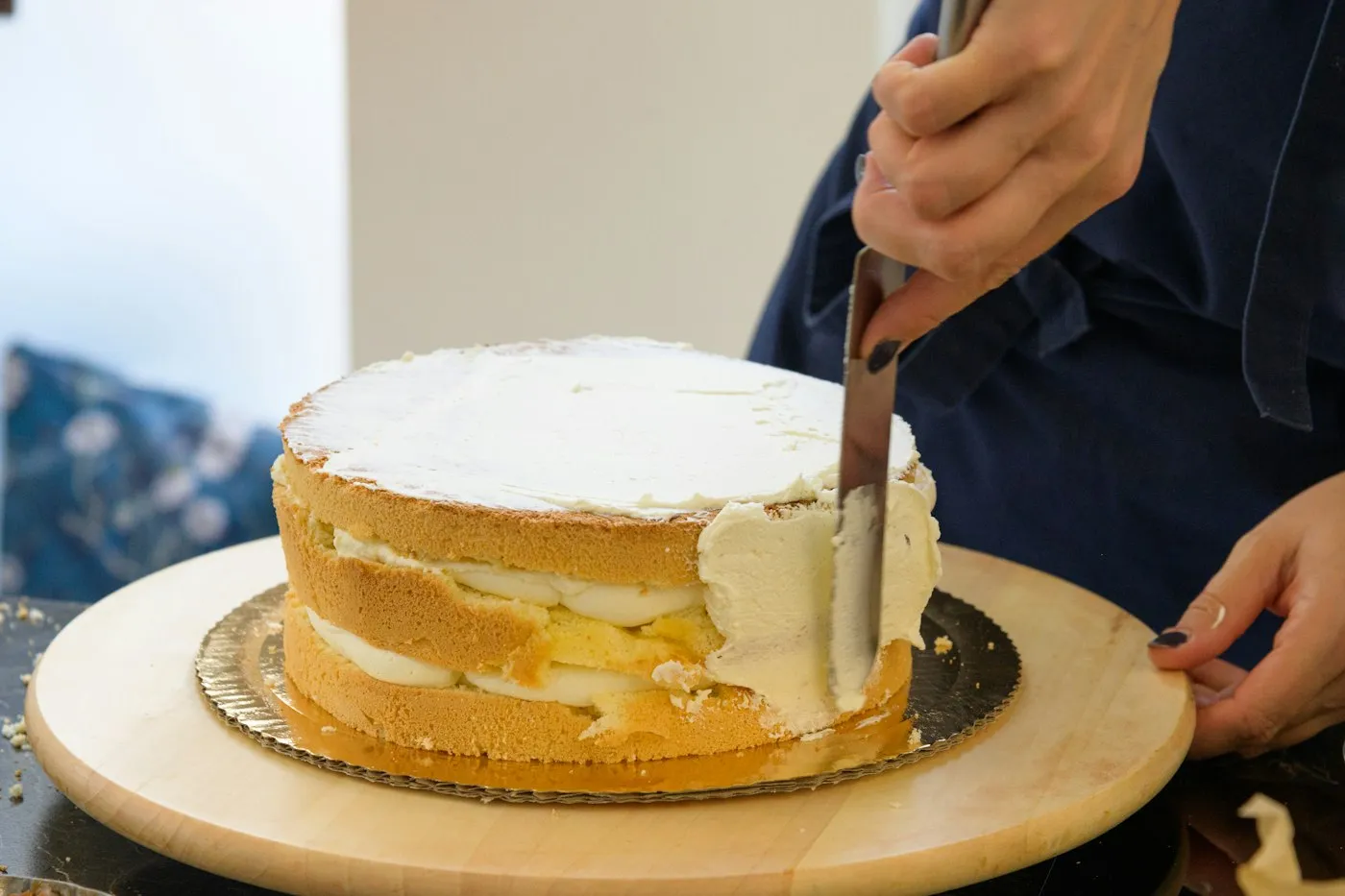 Pastelera cubriendo un pastel con betún